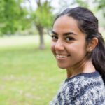 happy pretty young woman posing at camera in park